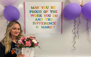 Nurse holding present in front of banner