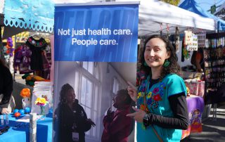 AHS staff posing with banner at Dia De Los Muertos event 2024.