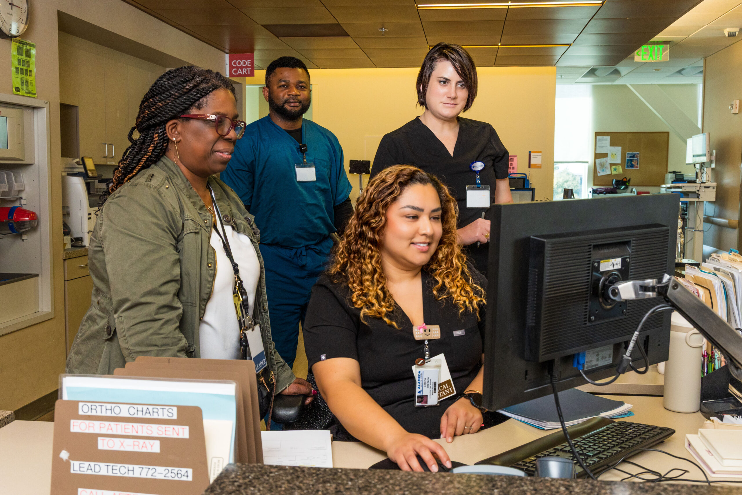 Diverse nurses huddled around computer.